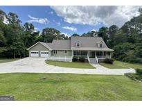 Charming home featuring a welcoming front porch and a spacious driveway, surrounded by lush trees and a well-manicured lawn at 3133 Callie Still Rd., Lawrenceville, GA 30045