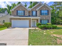Two-story brick home featuring a two-car garage, white trim, and landscaped front yard at 325 Espana St, South Fulton, GA 30349
