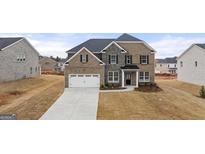 Two-story home with a brick and stone facade, two-car garage, and well-maintained lawn at 1804 Quaker St, Hampton, GA 30228