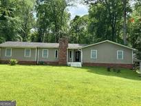 Charming single-story home with a brick chimney and neutral siding, nestled in a wooded area at 142 Carrollwood Dr, Fayetteville, GA 30215