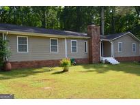 Ranch-style home with brick foundation, chimney, green lawn, neutral siding, and inviting front entrance at 142 Carrollwood Dr, Fayetteville, GA 30215