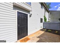 Back door entrance with black metal screen door, small patio and 'Stay Awhile' welcome mat at 313 Country Club Dr, Jonesboro, GA 30238