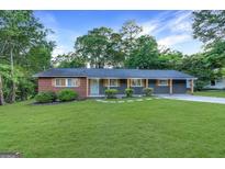 Charming single-story home featuring a brick and gray facade, complemented by a lush green lawn and mature trees at 1091 Pine St, Conyers, GA 30012