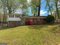 Charming split-level home with brick facade, red shutters, and colorful landscaping on a lush green lawn at 5637 Sturbridge Way, South Fulton, GA 30349