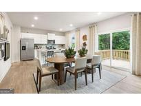 Bright dining room features a wood table, with views to an open kitchen and outdoor deck at 8502 Polston Place # 144, Douglasville, GA 30134