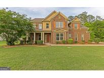 Charming two-story brick home with well-manicured lawn and mature trees at 321 Champions Dr, Fairburn, GA 30213