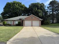 Charming single-story brick home with a well-manicured lawn and two car garage at 6050 Great Oaks Dr, Lithonia, GA 30058