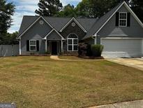 Charming single Gathering home with stone accents, gray siding, a well-manicured lawn, and a two car garage at 556 Walton Dr, Social Circle, GA 30025