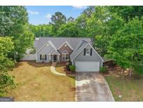 Charming single-Gathering home featuring gray siding, stone accents, and a two-car garage at 556 Walton Dr, Social Circle, GA 30025