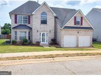 Charming two-story home with a well-maintained lawn, a two-car garage, and brick exterior at 1762 Wood Stork Drive, Hampton, GA 30228