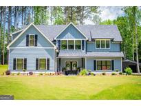 Charming two-story home with blue siding, black shutters, and a beautifully landscaped front yard at 457 Paynes Lake Rd, Carrollton, GA 30116