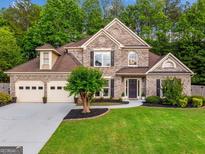 Charming two-story brick home featuring a manicured lawn, three-car garage, and professionally landscaped yard at 3707 Lance Bluff Ln, Duluth, GA 30097