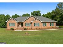 Charming brick home with green shutters, well-manicured lawn and beautiful landscaping at 604 Clearwater Ct, Mcdonough, GA 30252