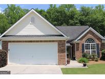 Charming brick home with an attached two-car garage and a well-maintained front lawn at 300 Cloverwood Dr, Fayetteville, GA 30215