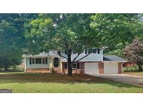 Charming home with a well-maintained lawn, mature trees, and a two-car garage at 1102 Tony Valley Se Dr, Conyers, GA 30013