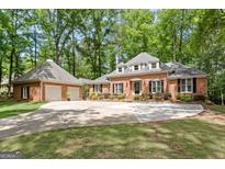 Stunning brick home with a well-manicured lawn and a long driveway leading to an attached two car garage at 145 Oxford Ln, Fayetteville, GA 30215