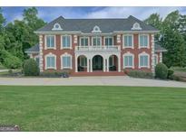 Stately brick home with a manicured lawn and grand entrance featuring a balcony and columns at 205 Somerset Ct, Mcdonough, GA 30253