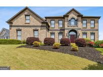 Stunning brick home featuring a lush front lawn and meticulously landscaped shrubbery for enhanced curb appeal at 3823 Heritage Pl, Buford, GA 30519