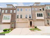 View of townhome exteriors with brick and vinyl siding and attached garages, offering curb appeal and convenient parking at 1106 Bakary Ct, Decatur, GA 30032