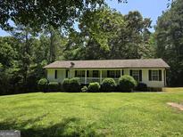 Charming home featuring a covered porch, a well-manicured lawn, and lovely landscaping at 220 Jackson Rd, Mcdonough, GA 30252