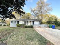 Charming single-story home with a gray brick facade, manicured lawn, and a long, paved driveway at 2860 Lynda Pl, Decatur, GA 30032