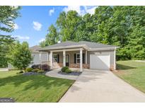 Charming single-story home featuring a welcoming front porch, well-manicured lawn, and attached one car garage at 385 Orchard Land, Covington, GA 30014