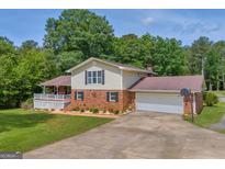 Two-story home with a brick and vinyl exterior, attached garage, long driveway, and manicured lawn at 6023 Highway 20 S, Covington, GA 30016
