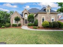 Charming brick home with manicured lawn, lush landscaping, and inviting curb appeal at 719 Bethpage Dr, Mcdonough, GA 30253