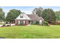 Beautiful single-story brick home with well-manicured lawn and mature trees offering great curb appeal at 235 Surrey Park Dr, Fayetteville, GA 30215