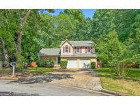 Charming two-story home features a two-car garage, red shutters, and is surrounded by lush greenery at 11203 Hemlock Rd, Hampton, GA 30228