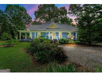 Charming blue home with a covered porch, lush landscaping, and a welcoming gravel driveway at 7550 Fielder Rd, Jonesboro, GA 30236