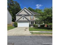 Charming two-story home featuring a two-car garage and inviting front porch nestled among mature trees at 590 Dot Dr, Atlanta, GA 30349