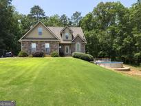 Charming two-story home featuring stone accents, a well-manicured lawn, and an inviting above ground pool at 200 Scouts Ridge Dr, Covington, GA 30016