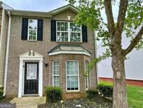 Charming brick townhome featuring black shutters and a well-manicured front yard at 1843 Grove Way, Hampton, GA 30228