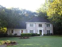Traditional brick home featuring a manicured lawn, complemented by lush landscaping and mature trees at 4786 Carlene Sw Way # Iv, Lilburn, GA 30047