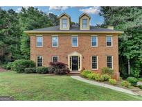 Charming two-story brick home featuring dormer windows and mature landscaping at 1486 Maple Ridge Dr, Suwanee, GA 30024