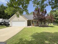 Charming single-story home with well-maintained lawn, two-car garage and mature landscaping at 105 Carols Ln, Locust Grove, GA 30248