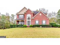 Stunning two-story brick home with a manicured lawn, complemented by lush shrubbery and mature trees at 1373 Fall River Dr, Conyers, GA 30013
