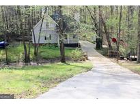 Secluded two-story home in the woods, featuring a charming porch and a long driveway leading to the property at 142 Kylee Ct, Villa Rica, GA 30180