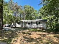 Charming single-story home with a large yard surrounded by trees and a long driveway at 324 Bells Ferry Ne Rd, White, GA 30184
