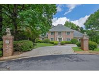 Stately brick home featuring a circular driveway, lush landscaping, and two decorative lion statues at the entrance at 2795 Hawthorne Dr, Atlanta, GA 30345