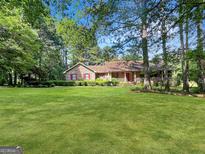 Charming brick home with lush lawn and mature trees offers great curb appeal at 120 Rolling Brook Trl, Fayetteville, GA 30215