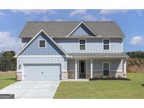Charming two-story home featuring light blue siding, a gray roof, a two-car garage and a well manicured front yard at 615 Cantrell Drive, Dallas, GA 30157