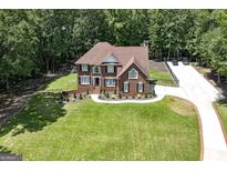 Beautiful brick home featuring a lush lawn, mature trees, and a long driveway at 20 Allie Dr, Mcdonough, GA 30252