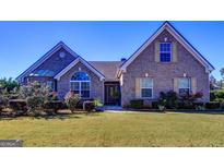 Charming brick home featuring a well-maintained lawn, mature landscaping, and inviting entryway with decorative door at 3008 Brighton Ct, Conyers, GA 30094