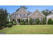 Imposing two-story brick home with manicured lawn and lush landscaping, shutters, and covered entry at 2750 Brentwood Estates Ct, Cumming, GA 30041