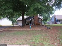 Charming single-story home with brick chimney and a cozy front porch swing, shaded by a large tree at 435 Rosehill Dr, Mcdonough, GA 30253