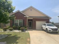 Charming one-story brick home with well-manicured lawn and inviting curb appeal on a sunny day at 2635 Lovejoy Crossing Ln, Hampton, GA 30228