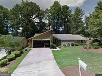 Charming single-story home featuring a well-manicured lawn and attached garage, nestled among mature trees at 100 Lake Forest Dr, Peachtree City, GA 30269