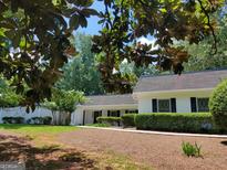 Charming single-story home featuring black shutters, lush landscaping, and a brick exterior at 7640 Ryefield Dr, Sandy Springs, GA 30350